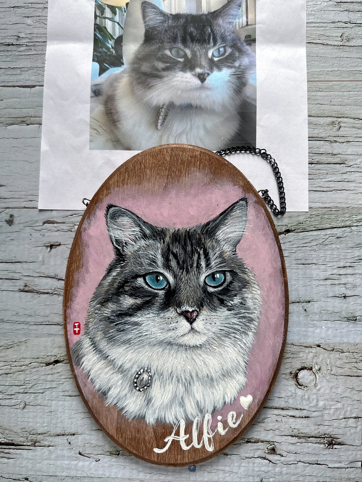Cat portrait wood plaque laid flat beside the customer's photo of the cat, painted from the photo