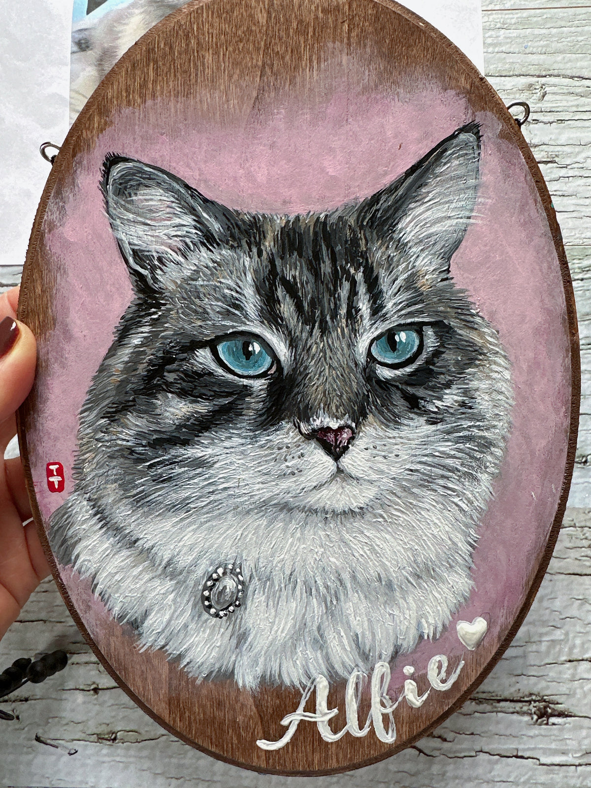 Close-up of the hand-painted cat's lifelike blue eyes and fine fur detail with the name Alfie and a small heart